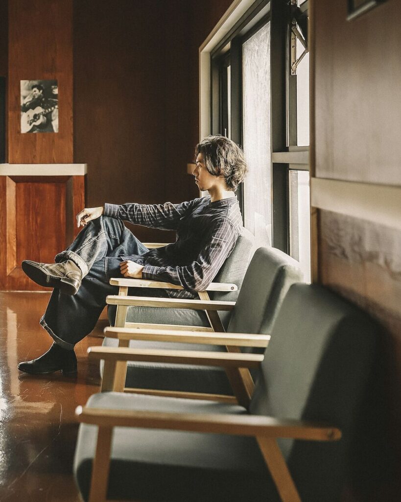 Patient sitting by a tall window in a warm, wood-panelled waiting area
