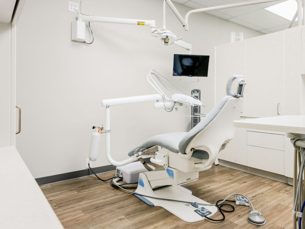 Treatment room with a pale dental chair on a warm wood floor