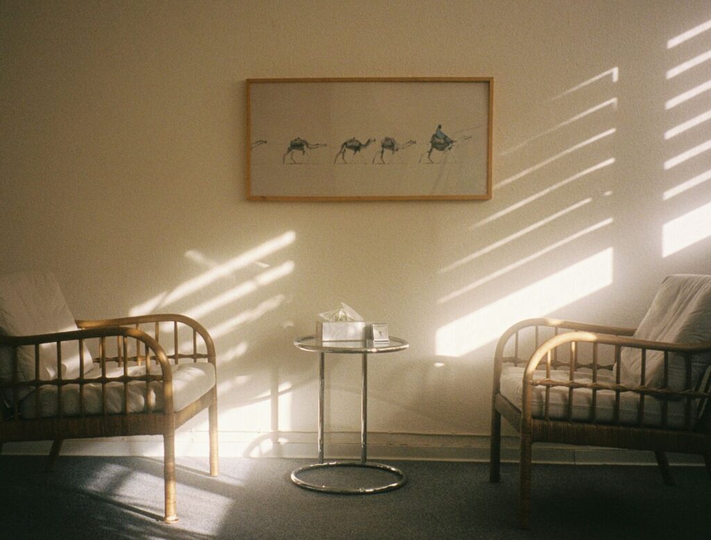 Sunlight falling across two armchairs and a small table in a quiet waiting area